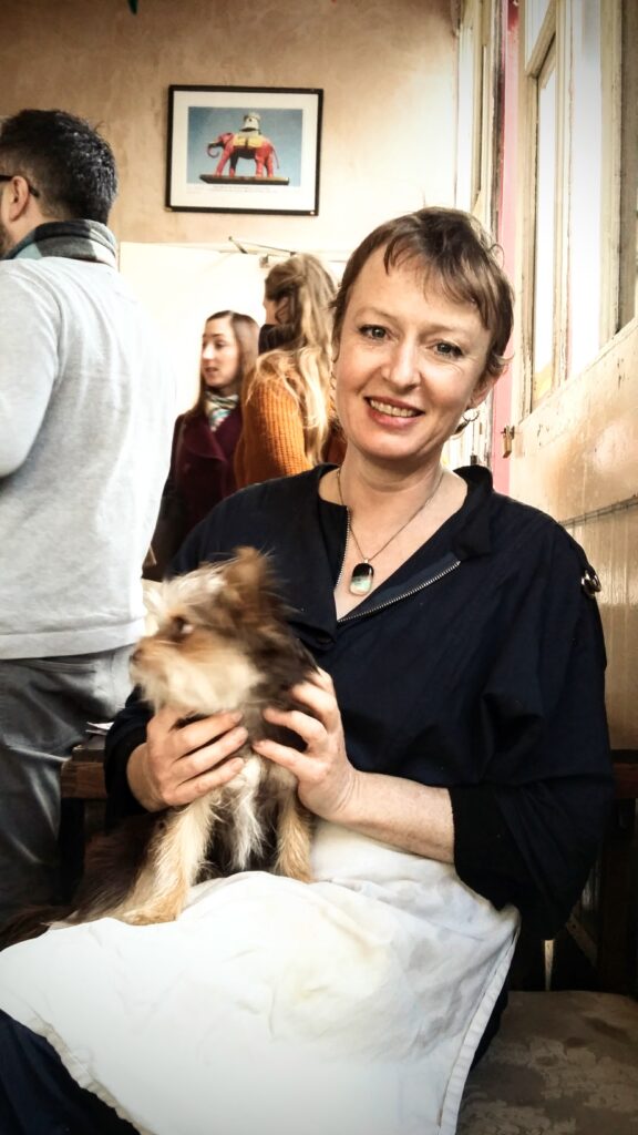 Portrait of Louisa Cath, The Electric Elephant Cafe's owner, in the cafe, smiling with a small dog on her lap